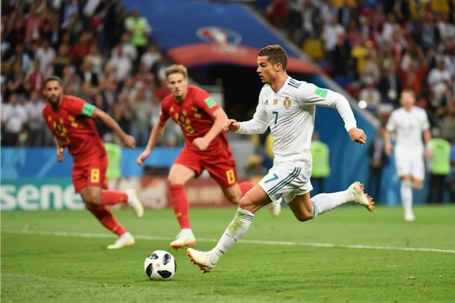 一位欧洲足球明星在决赛中带球突破，身后是紧追不舍的防守球员与激动人心的观众